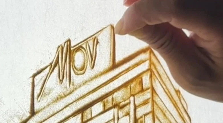 サンドアートで「MOV」の文字が描かれた建物