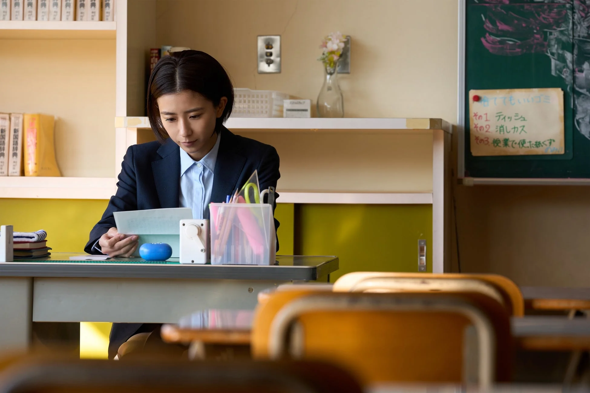 教室で書類を読む教師・真唯子